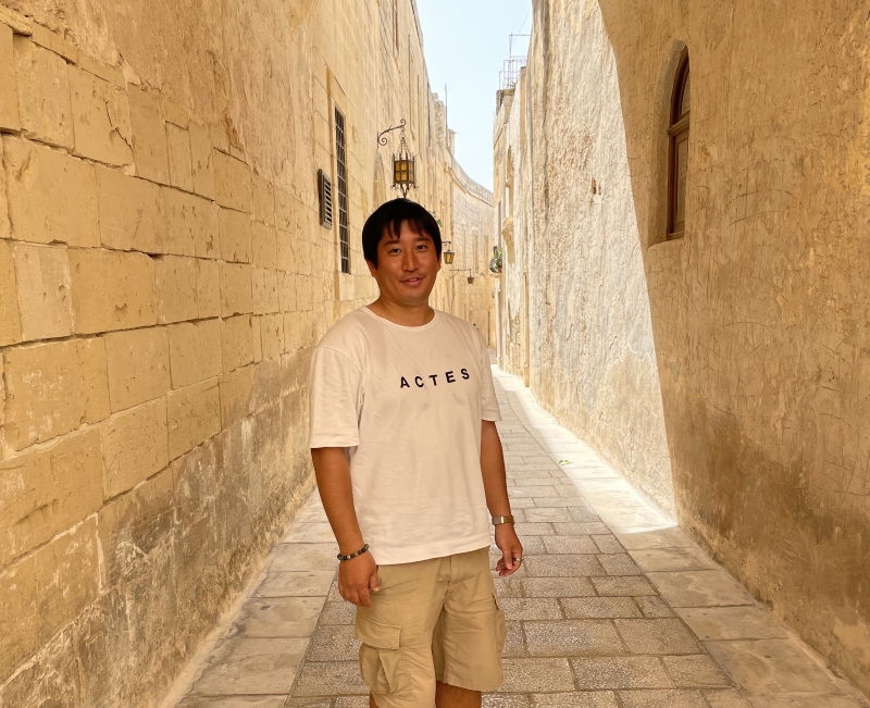 株式会社ウェルネシス(wellnesis)代表の貝瀨郁弥が海外路地で微笑んで立っている写真